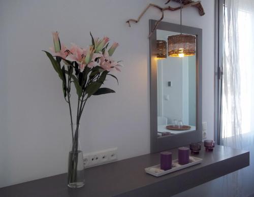 a vase with pink flowers on a counter in a bathroom at Mare Dei Suites Hotel Ionian Resort in Skafidia
