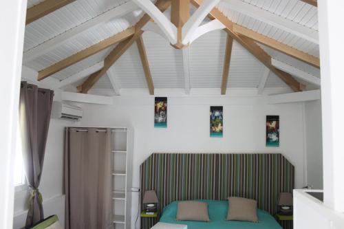 a bedroom with a green bed and wooden ceilings at Résidence B&L Lagon : Bungalow Atoll in Sainte-Luce