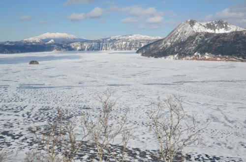 a snow covered field with mountains in the background at ARtINn 極寒藝術伝染装置 in Teshikaga