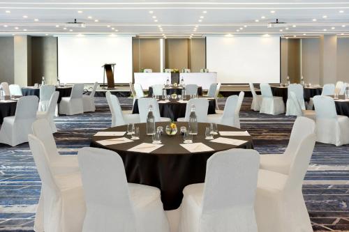 a conference room with tables and white chairs at Novotel Jakarta Cikini in Jakarta