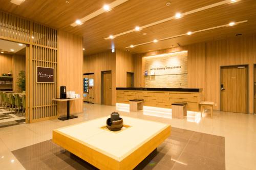 a lobby with a table in the middle of a building at Dormy Inn Express Kakegawa in Kakegawa