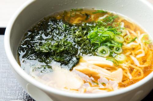 a bowl of soup with noodles and greens in it at Dormy Inn Express Kakegawa in Kakegawa
