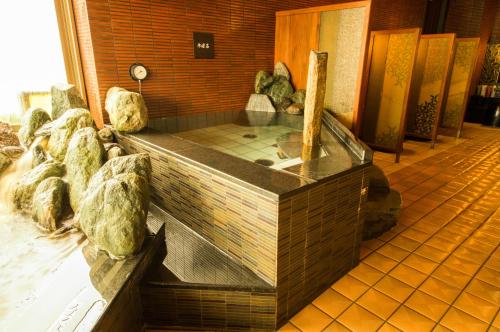 a hot tub in a room with rocks at Dormy Inn Express Kakegawa in Kakegawa