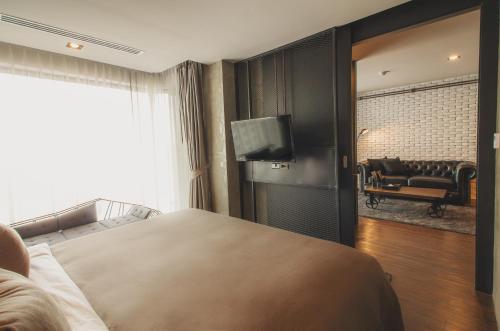 a bedroom with a bed and a couch and a television at S Hadyai Hotel in Hat Yai