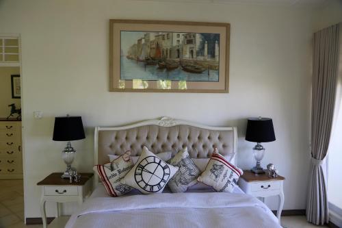 a bedroom with a bed with pillows and a painting on the wall at Pondok Plantation Luxury Mountain Escape Bedugul in Bedugul