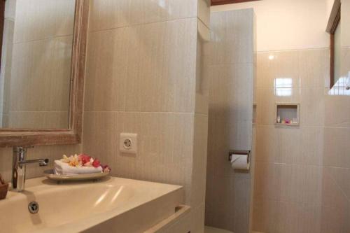 a bathroom with a sink and a mirror and a shower at Arsa Wayan Guest House in Klungkung