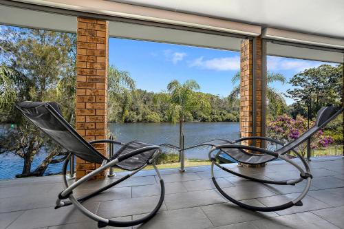 two chairs on a porch with a view of a river at Bonville on Bonville in Sawtell