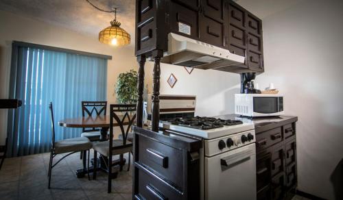 a kitchen with a stove and a table with a microwave at Hotel Suites Malena in Ensenada