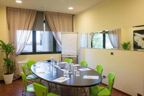 a conference room with a table and green chairs at Hotel Bologna Airport in Bologna