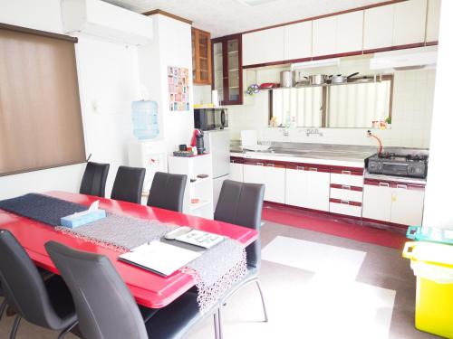 a kitchen with a red dining table and chairs at Holiday Homes TSUBOYA 2nd in Naha
