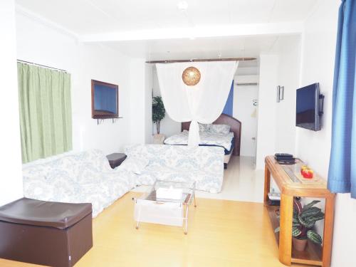 a living room with a couch and a bed at Holiday Homes TSUBOYA 2nd in Naha