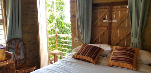 Bett mit zwei Kissen vor einem Fenster in der Unterkunft Pumdikot Mountain Lodge in Kāskī