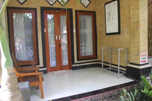 a building with a porch with a chair and windows at Nitya Home Stay Lembongan in Nusa Lembongan