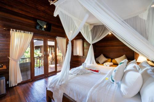 a bedroom with a canopy bed with white pillows at Royal Cottage Nusa Lembongan in Nusa Lembongan