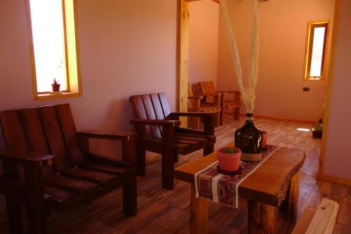 a living room with chairs and a table and a vase at Casa Ckelar Atacama in San Pedro de Atacama