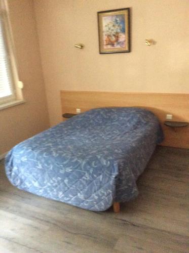 1 dormitorio con 1 cama con edredón azul en Le Trianon, en Hesdin