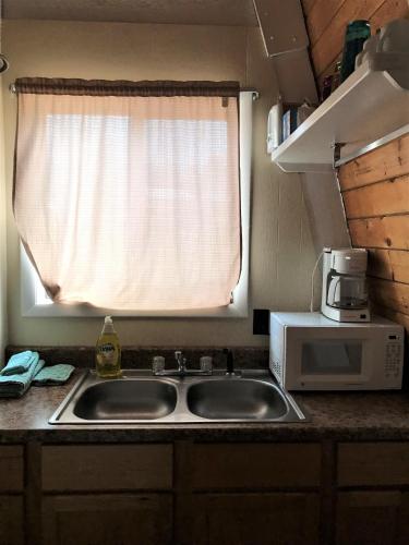 a kitchen sink with a microwave and a window at Drift Lodge in Island Park