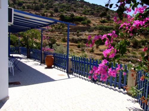 a blue fence with pink flowers on a hill at Villa Costa Studios in Vathi, Sifnos