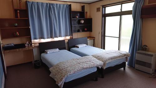 two twin beds in a room with a window at Shukubo Daishinbo in Tsuruoka