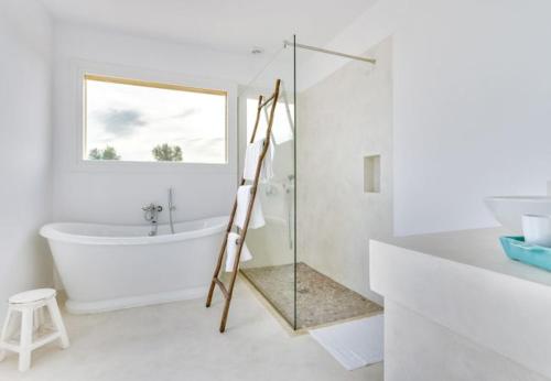 a white bathroom with a tub and a glass shower at Finca El Idilio in Ses Salines