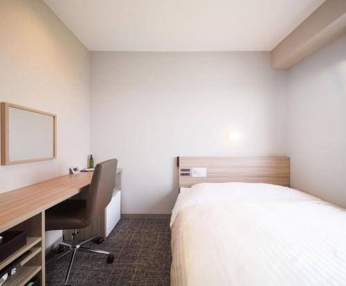 a room with a bed and a desk and a desk at Super Hotel Anan Tomioka in Anan