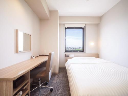 a bedroom with a desk and a bed and a desk and a window at Super Hotel Anan Tomioka in Anan