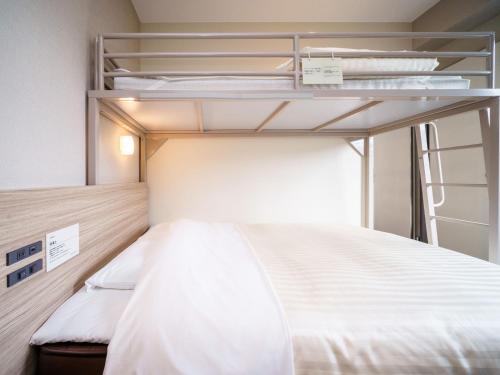 a bedroom with two bunk beds with white sheets at Super Hotel Anan Tomioka in Anan