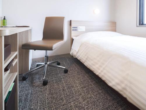 a bedroom with a desk and a chair next to a bed at Super Hotel Anan Tomioka in Anan