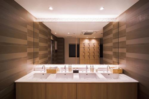 a bathroom with three sinks and a large mirror at Super Hotel Anan Tomioka in Anan