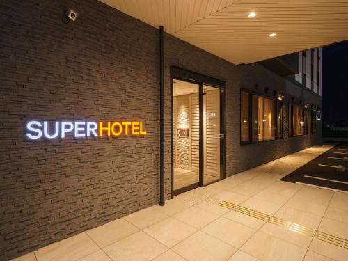 a sign for a super hotel on the side of a building at Super Hotel Anan Tomioka in Anan