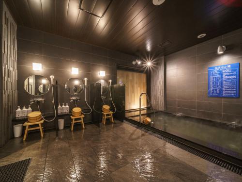 a bathroom with two sinks and a bathtub with mirrors at Super Hotel Anan Tomioka in Anan