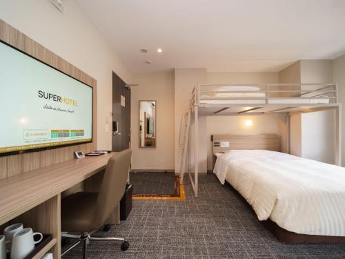 een hotelkamer met een bed en een projectiescherm bij Super Hotel Anan Tomioka in Anan