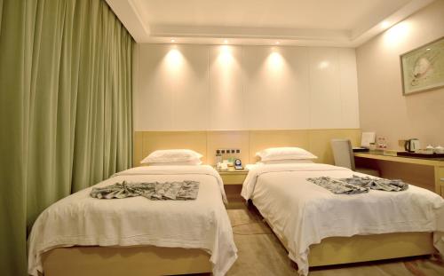 two beds in a hospital room with green curtains at Dunhuang Hotel in Dunhuang