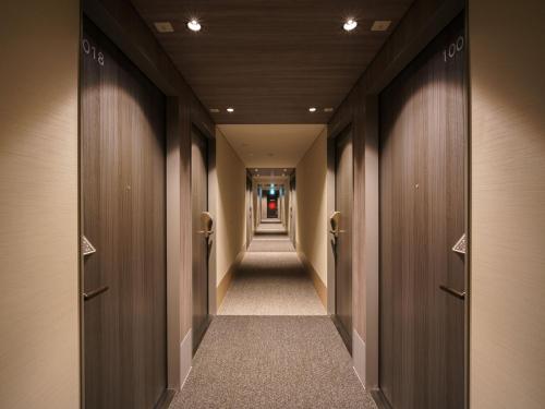 a corridor of a hallway with wooden doors at Super Hotel Anan Tomioka in Anan