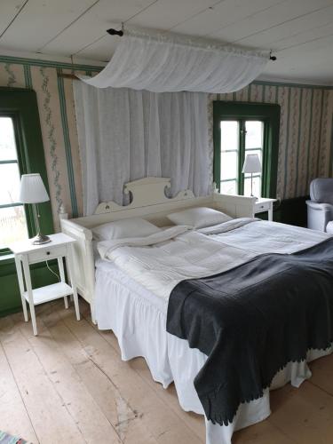 a bedroom with a large white bed and two tables at Hofra Bed & Breakfast in Delsbo
