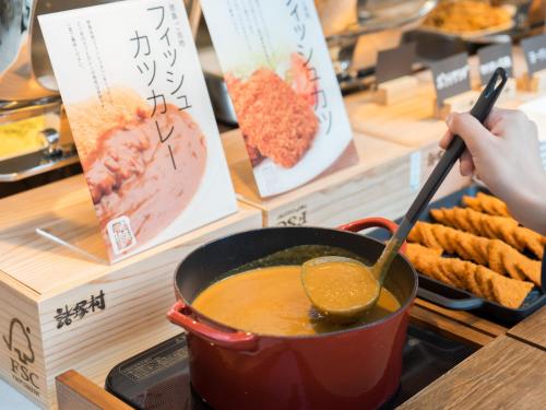a person is stirring a pot of soup on a counter at Super Hotel Anan Tomioka in Anan