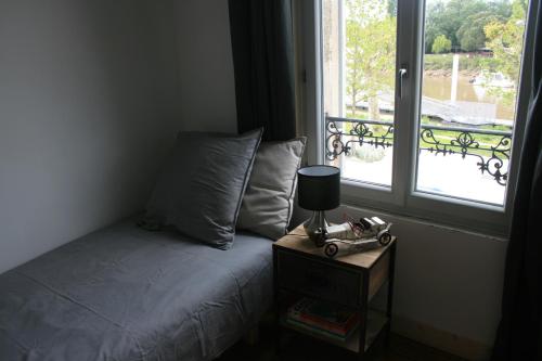 una cama con mesita de noche junto a una ventana en QUAI SOUCHET en Libourne