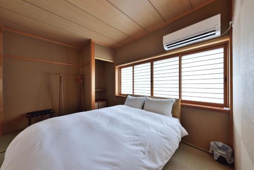 a bedroom with a white bed and a window at Comfortable House In Fushimi 2 in Kyoto