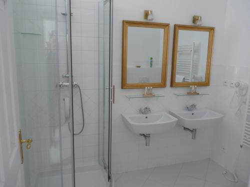 a white bathroom with two sinks and a shower at Zámek Napajedla in Napajedla