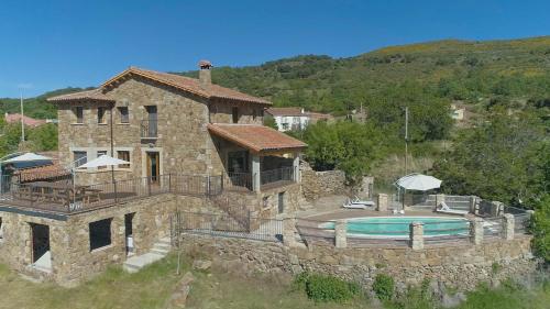 uma grande casa de pedra com piscina em Casas Rurales Lalo y Chelo em La Aldehuela