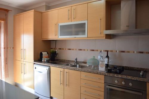 een keuken met houten kasten en een wastafel bij Apartamento T2 Vista Mar in Nazaré