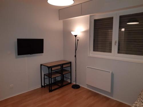a room with a lamp and a television on a wall at Charmant Studio in Metz