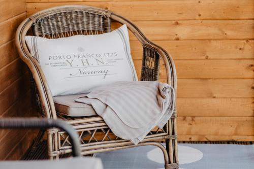 a wicker chair with a pillow in front of a wooden wall at Tumiło in Dziwnów