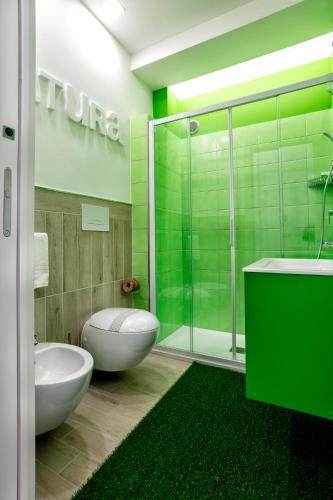 a green bathroom with a toilet and a shower at Manzoni Elements in Milazzo