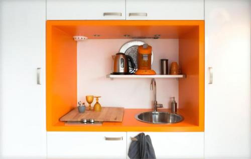 アムステルダムにあるハウスボート アーク ヴァン アムステルのオレンジ色のキャビネット内のシンク付きのキッチン