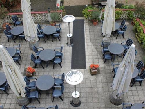 un patio al aire libre con mesas, sillas y sombrillas en Hotel Winneburg en Cochem