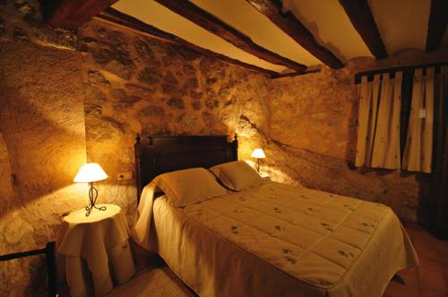 a bedroom with a bed and a table with a lamp at Apartamentos Los Tremedales in Orihuela del Tremedal