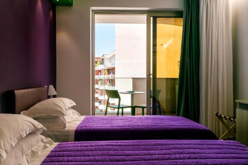 a bedroom with two beds with purple sheets and a window at Manzoni Elements in Milazzo