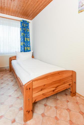a wooden bed in a room with a window at Haus Hafeneck mit Frühstücksoption in Bensersiel