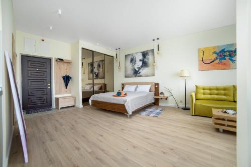 ein Schlafzimmer mit einem Bett und einer gelben Couch in der Unterkunft Студия в стиле лофт с прекрасным видом на город и красивые закаты! in Odessa
